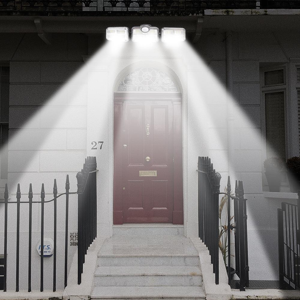 A highly lit red door with the 3 headed security light above