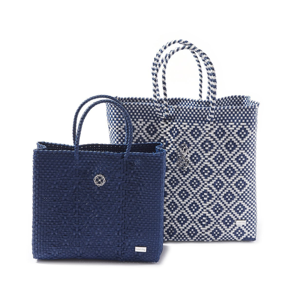 A MEDIUM BLUE AZTEC TOTE BAG shown along with another one that is white with blue checkered diamonds decorating it and slightly larger sitting behind it