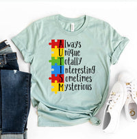 Thumbnail for An Autism T-shirt shown with puzzle pieces arranged vertically with words next to them reading Always Unique Totally Interesting Sometimes Mysterious in teal green with a pair of jeans sitting next to it and a pair of white shoes