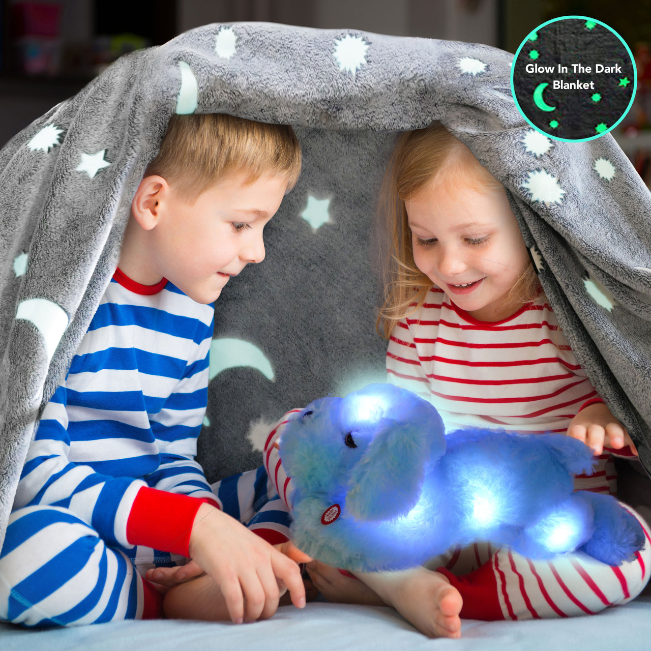 Shows two young children using the Microfiber Glow in the Dark Blanket & Pillow Set as a tent playing with the blue glow pet underneath