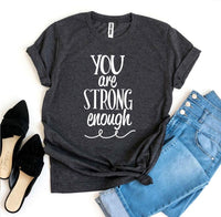 Thumbnail for A black and white You Are Strong Enough T-shirt shown with a pair of jeans next to it and a pair of black heels