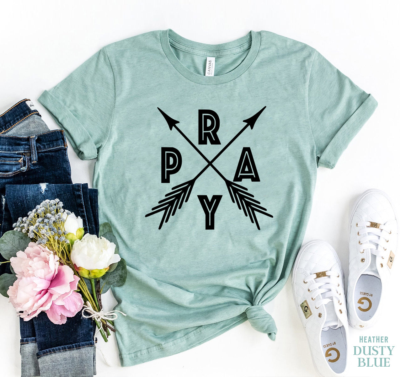 Pray T-shirt shown in teal green with black words pray has a pair of jeans sitting next to it and a pair of white tennis shoes