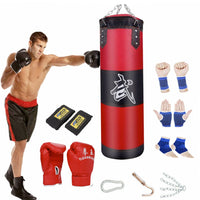 Thumbnail for A Boxing Trainer Fitness Punching Bag Set shown with a male model shown striking the heavy bag with various included items sitting around the bag such as red gloves wrist wraps and carabiners for hanging the bag