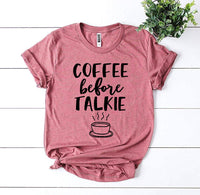 Thumbnail for Pink Coffee Before Talkie T-shirt shown sitting on ship lap board with a green plant next to it