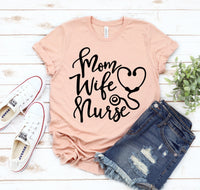 Thumbnail for A Mom Wife Nurse T-shirt shown in peach sitting on white wooden deck with jeans and a pair of white tennis shoes sitting beside it